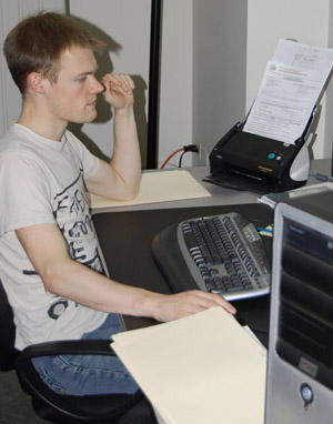 Planning + information specialist Ben Tatterton scans the cover sheet of a City development circulation for online access by BPG participants.